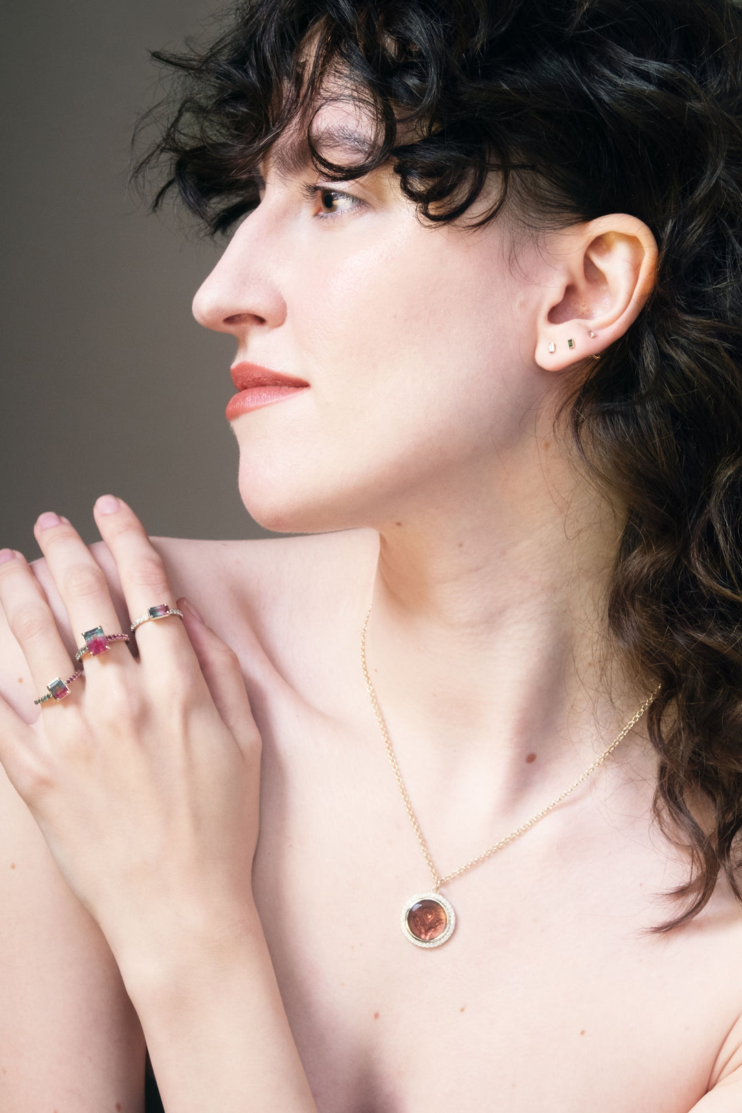 woman with curly dark hair wearing new rings and a pendant