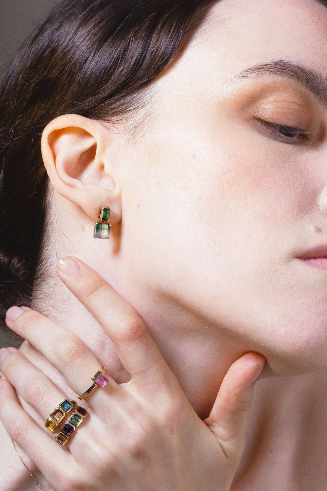 close up of womans hand and ear wearing genevieve schwartz jewellery colourful gemstone pieces. Eye is part closed.