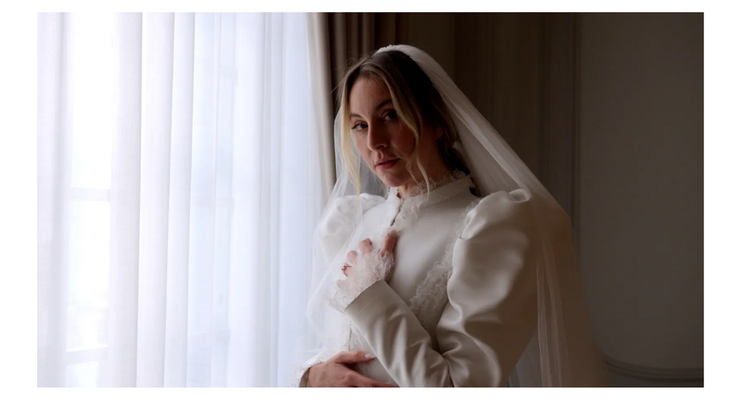 este haim standing by window in wedding dress wearing Genevieve Schwartz engagement ring