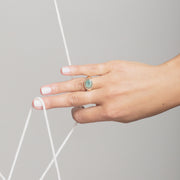 womans hand wearing a chrysoprase ring holding onto a white string