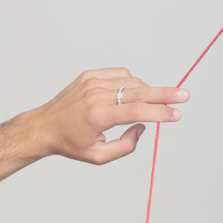 white gold mens engagement ring on mans hand holding onto tugged red string